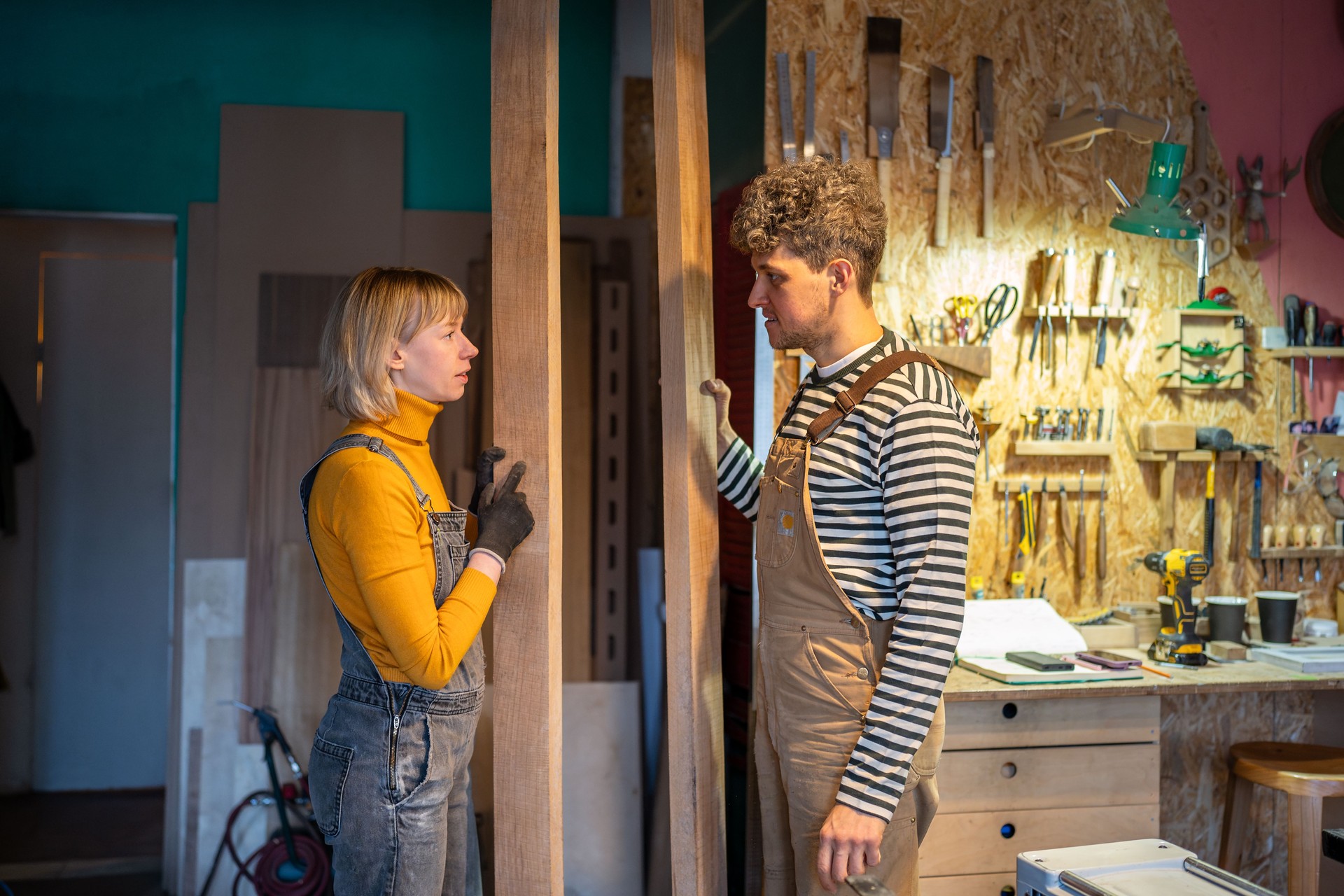 Carpentry partners with wood timber beams exchanging ideas about upcoming tasks in woodworking shop