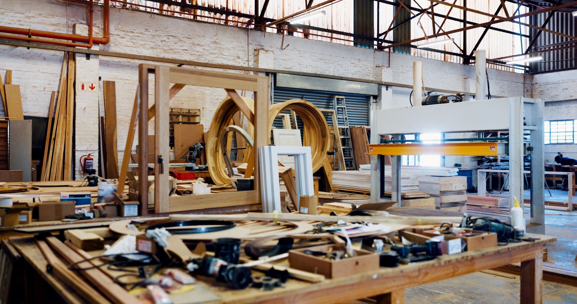 Woodworking, machine and tools in factory, manufacturing and material with lumber, craft and construction. Empty, warehouse and small business with equipment, furniture, carpentry or industrial space